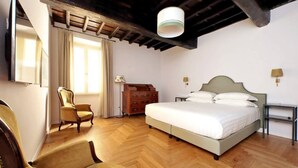 Une chambre à coucher avec un lit, un plancher en bois, une chaise, une commode et une lampe.