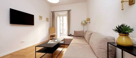 Una sala de estar moderna con un sofá, una mesa de centro, un televisor montado en la pared y una lámpara.