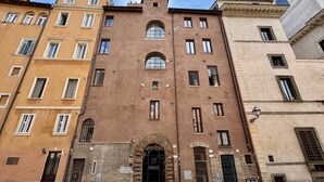 Un immeuble à plusieurs étages, doté d’une entrée centrale en arc de cercle, de nombreuses fenêtres et d’une façade en briques.