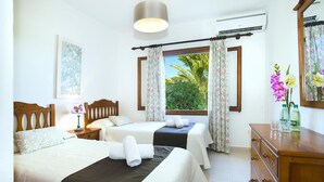 Een hotelkamer met twee bedden, een dressoir, een raam met gordijnen, een lamp en een ingelijst kunstwerk aan de muur.