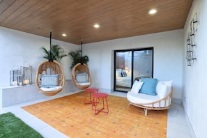 Un intérieur moderne avec un fauteuil suspendu, un canapé et une petite table.