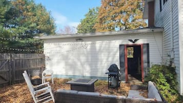 Relax in the backyard patio area, complete with a wicker sofa, table, and chair, and a grill for outdoor cooking.