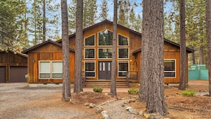 A wooden cabin with large windows, surrounded by trees.