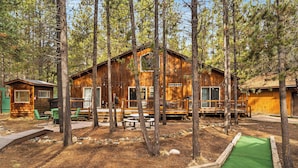 A rustic cabin with a deck, surrounded by trees.