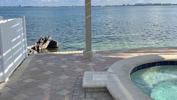 A pool area with a pergola, a view of the water, and a distant city skyline. - On the water and golf course view (St. Petersburg)