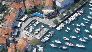 An aerial view of a marina with numerous boats docked, surrounded by buildings with red-tiled roofs. - Studio apartment in Ika with Balcony, Air condition, WIFI, Washing machine (5025-3) (Ika)