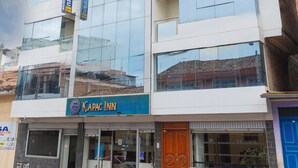 A multi-story building with a glass facade, a sign for 'Kapac Inn,' and a blue door. - kAPAC INN HOTEL (Cusco)