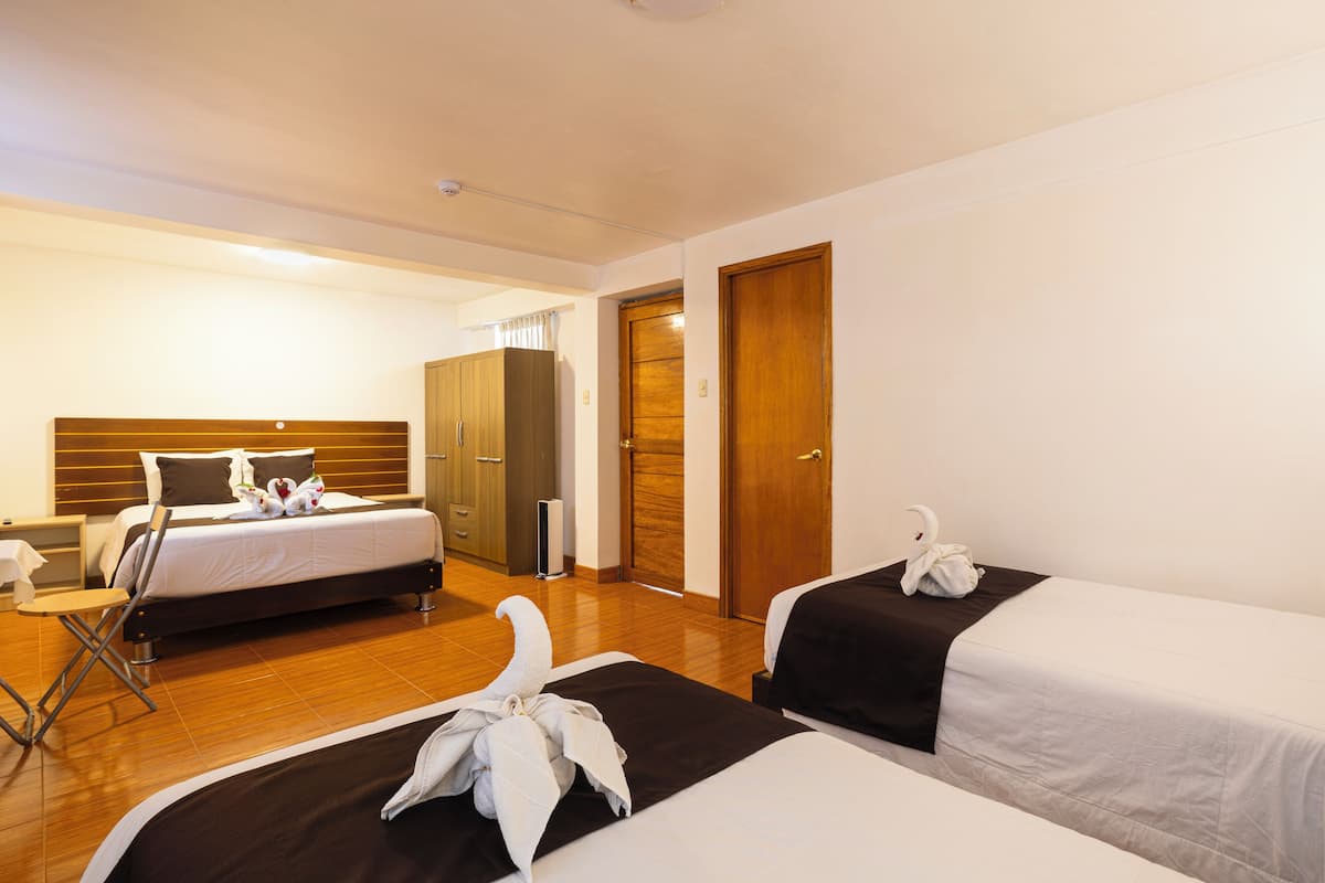A hotel room with a bed, a wardrobe, a desk, and a chair.