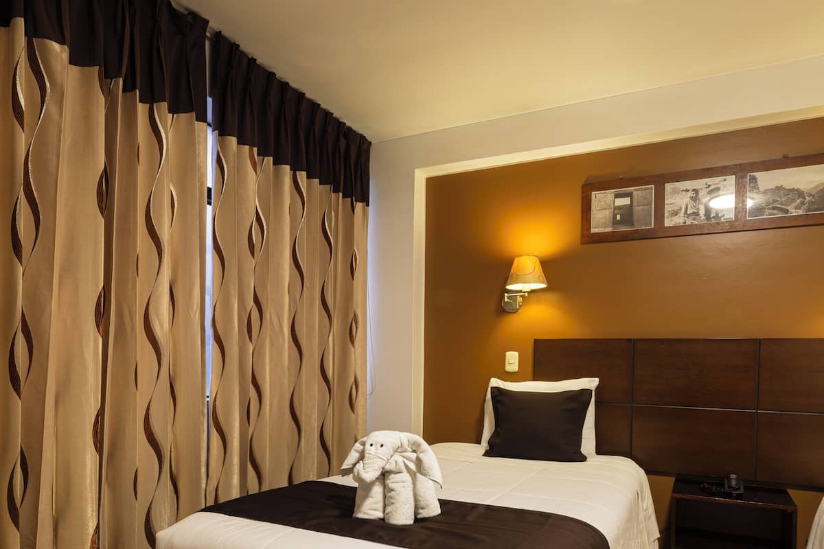 A hotel room with a large bed, a nightstand, a lamp, and a wall-mounted picture.