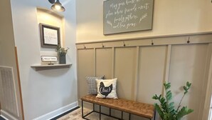 A hallway with a bench, a wall-mounted shelf with a sign, a framed picture, and a decorative sign. - Country Home near Chattanooga, Harrison Bay, Howe Farms, and Gray Dove venues! (Ooltewah)