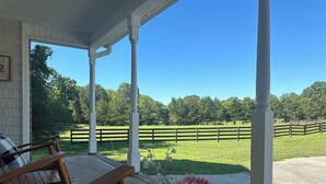 A covered porch with a wooden bench and a flower arrangement. - Country Home near Chattanooga, Harrison Bay, Howe Farms, and Gray Dove venues! (Ooltewah)