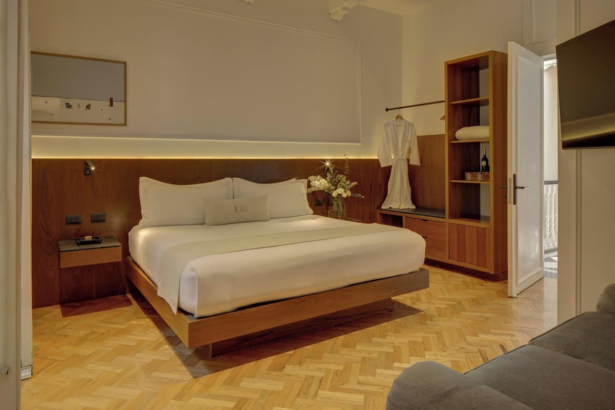 Un dormitorio moderno con un cabecero de madera, una cama grande, una mesita de noche, un armario y un espejo en la pared.