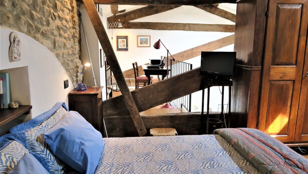 A bedroom with a bed, a wooden staircase, a desk with a chair, and a television. - Residence Lina (Brisighella)
