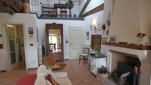 A spacious living room with a high ceiling, a fireplace, and a dining area. - Residence Lina (Brisighella)