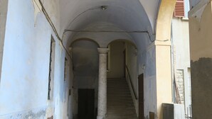 A corridor with arches, a tiled floor, and a staircase leading to an upper level. - Residence Lina (Brisighella)