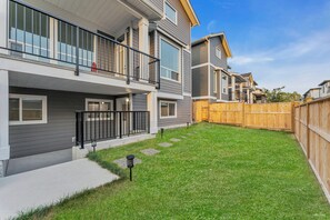 Ein modernes, zweistöckiges Wohnhaus mit Balkon, umzäunter Garten und gepflegtem Rasen.