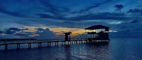 A pier extending into calm waters with a covered structure at the end.