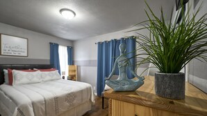 Een slaapkamer met een bed, nachtkastje, decoratieve vaas en een potplant.