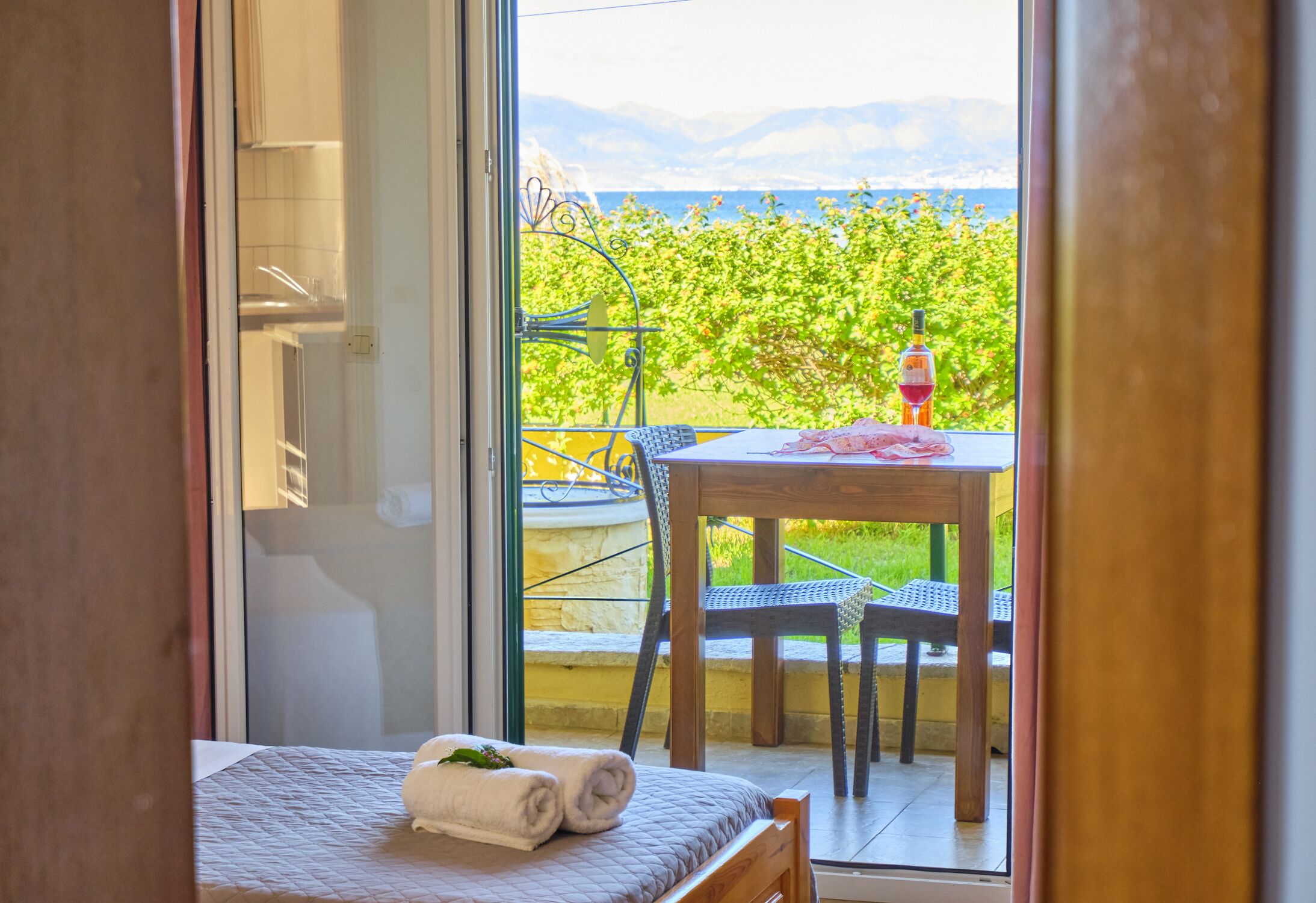 Ein Schlafzimmer mit Bett, Fenster und Blick auf Garten und Berge.
