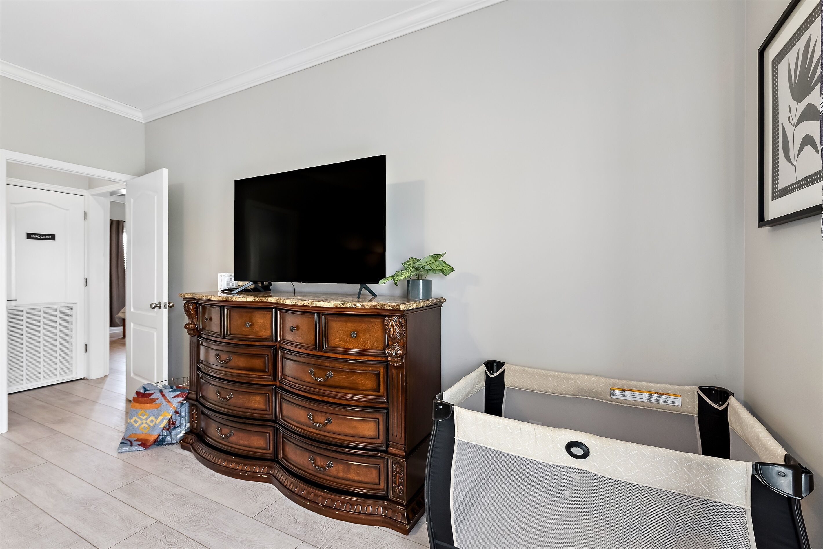 A room with a wooden dresser, a television, and a baby gate.