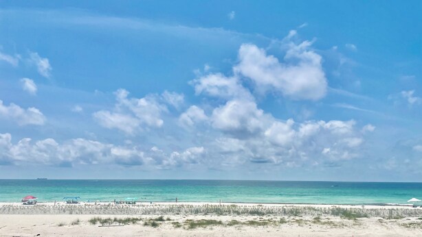 Une plage avec un ciel dégagé et une mer calme.