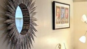 A striped sofa with geometric pillows, a sunburst mirror, and a framed artwork on the wall. - Romantic Luxury Artist Cottage Near French Quarter (New Orleans)