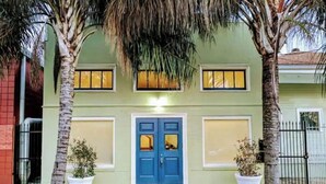 A two-story house with a blue front door, two windows on each floor, and two potted plants on either side of the entrance. - Romantic Luxury Artist Cottage Near French Quarter (New Orleans)