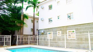 A swimming pool with a white fence, a ladder, and a palm tree. - Residency Hotel & Apartments (Abuja)