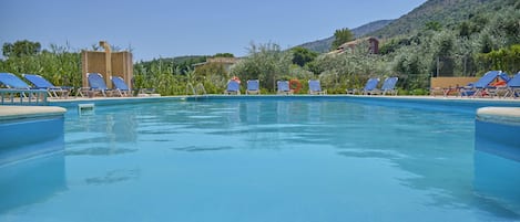 Piscina com espreguiçadeiras e montanhas ao fundo.