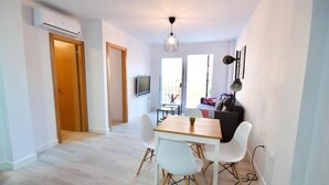 A modern living room with a dining area, a TV, and a sofa. - 2 bedroom apartment with large terrace (Málaga)