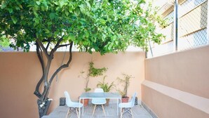 A patio with a table and chairs, surrounded by potted plants and a tree. - 2 bedroom apartment with large terrace (Málaga)