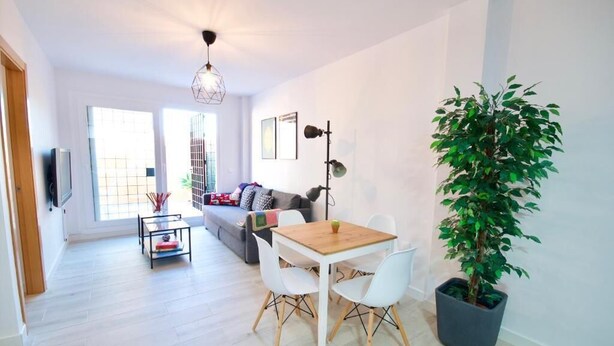 A modern living room with a dining area, a sofa, a coffee table, and a potted plant. - 2 bedroom apartment with large terrace (Málaga)