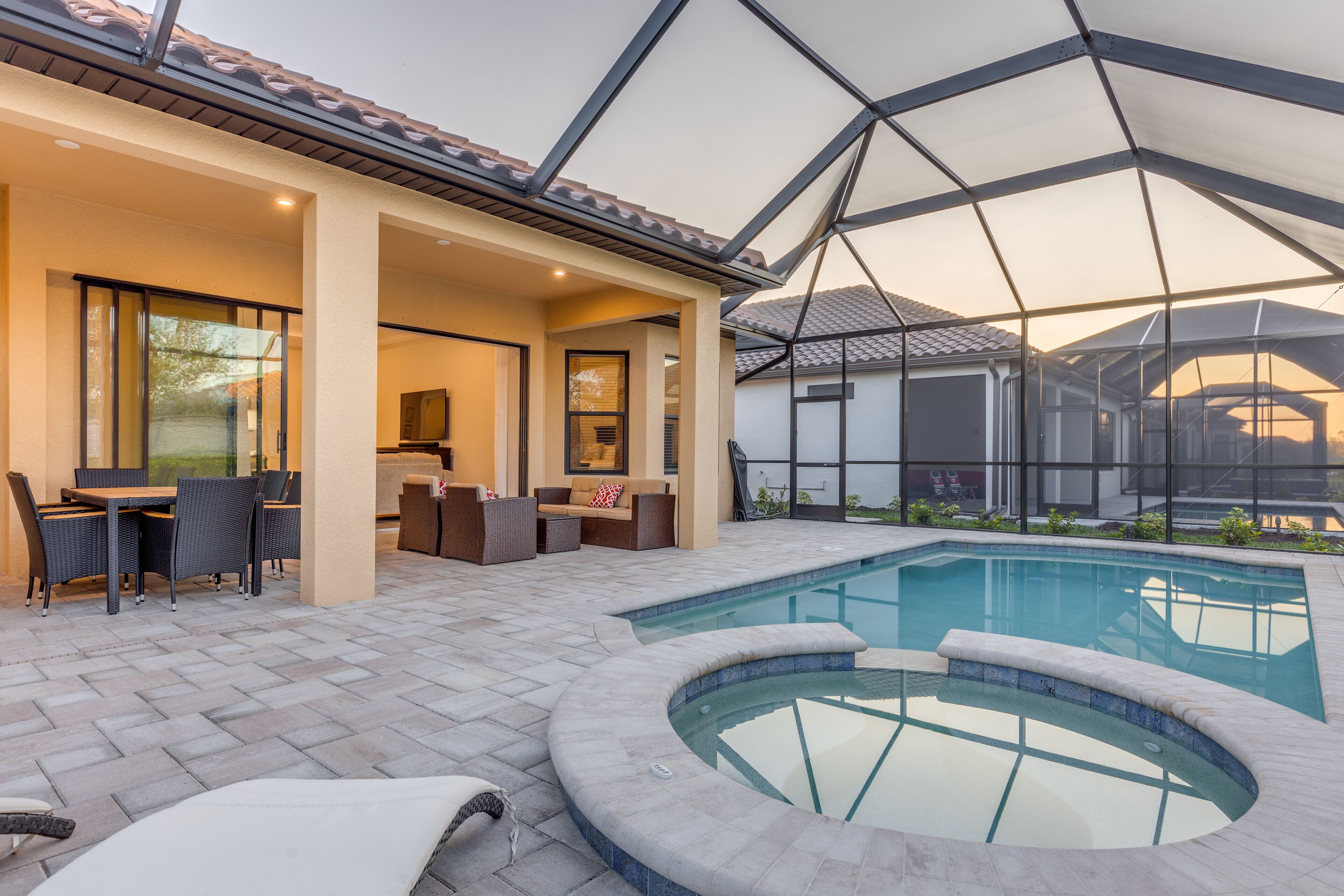 A pool area with a hot tub, outdoor seating, and a covered patio.