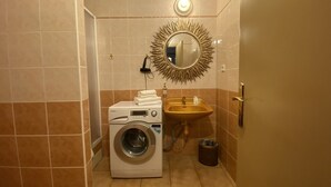 A compact bathroom with a washing machine, sink, and a decorative mirror. - Studio Golden 2 (Hlavní mesto Praha)