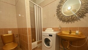 A bathroom with a toilet, washing machine, sink, and shower. - Studio Golden 2 (Hlavní mesto Praha)