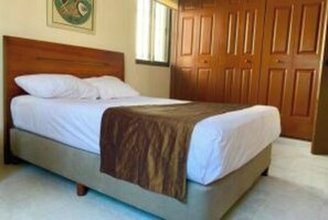 Cozy retreat with a single bed, wooden headboard, and wardrobe, set against a light-colored backdrop.
