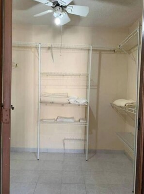Features a spacious walk-in closet with open shelving units and a ceiling fan.