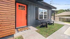 Una casa con puerta roja, una ventana y un banco en el exterior.