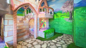 A children's playroom with a castle-themed design, including a staircase, a bed, and a window with a colorful stained glass. - Luxe 8BR Villa by Disney | Arcade and Private Pool (Kissimmee)