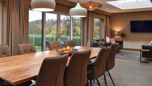 Un comedor moderno con una mesa y sillas de madera, un frutero y vistas al exterior.