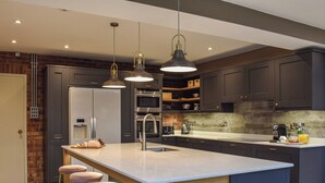 Cocina moderna con armarios oscuros, electrodomésticos de acero inoxidable y una isla central con taburetes de bar.