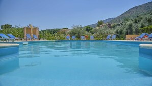 A swimming pool with lounge chairs and a mountainous backdrop.