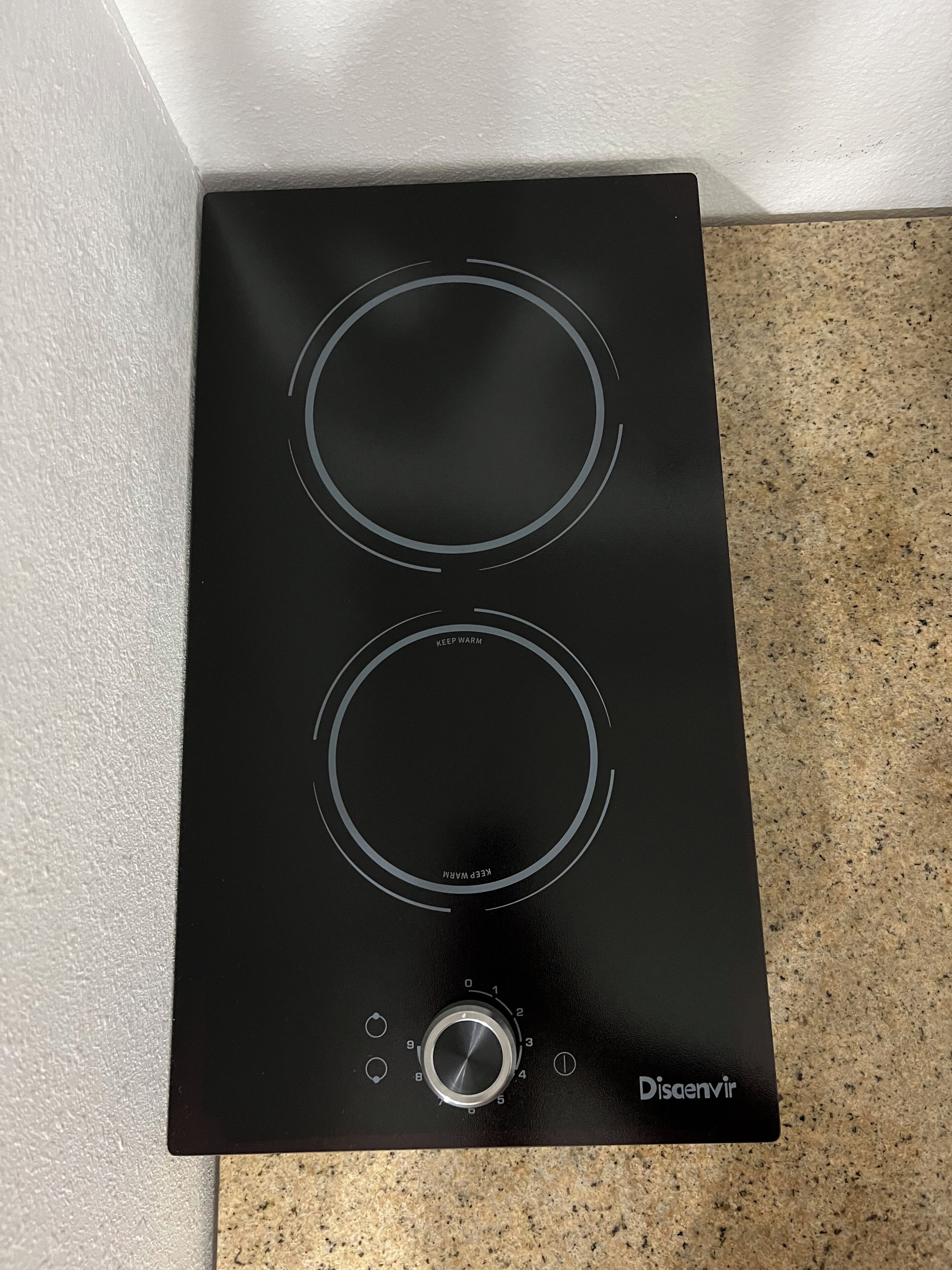 Una placa de cocina por inducción negra con dos resistencias circulares y una perilla de control.