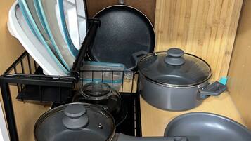 Une cuisine équipée d’une cuisinière, de casseroles, de poêles et d’une planche à découper.