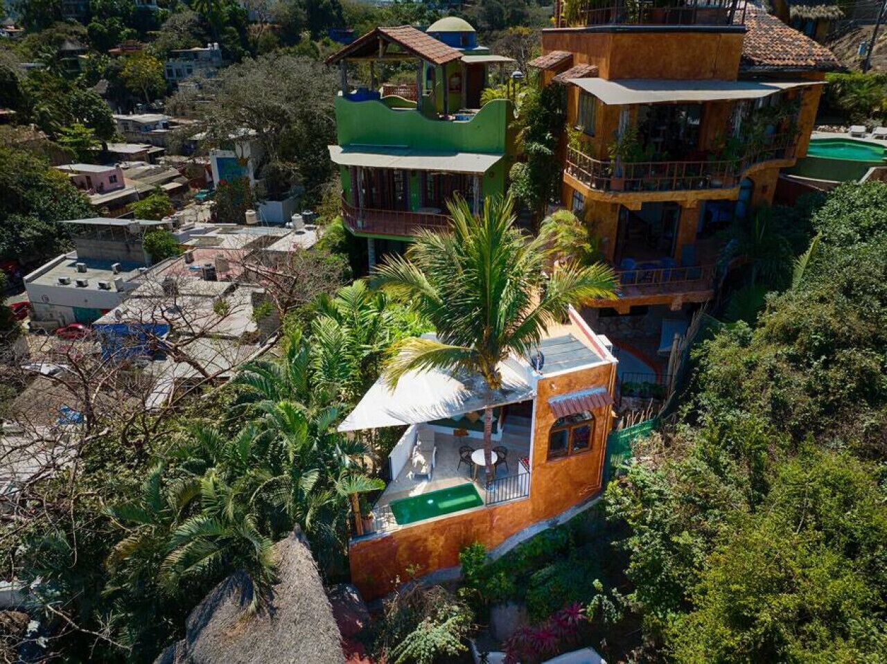 A multi-story building with a green roof, a balcony, and a small pool area.