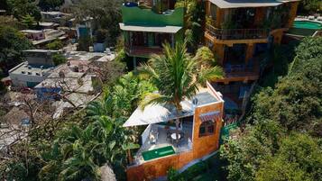 A multi-story building with a green roof, a balcony, and a small pool area.