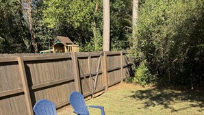 A backyard with two blue Adirondack chairs, a wooden fence, and a small wooden structure. - Five Points neighbor. Located 1.4 from UGA stadium. (Athens)