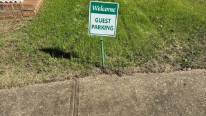 A welcome sign for guest parking in a grassy area with a brick structure and a metal ramp. - Five Points neighbor. Located 1.4 from UGA stadium. (Athens)