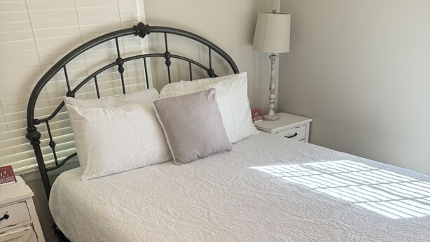A neatly made bed with a white quilt, a wooden floor, and a metal headboard. - Five Points neighbor. Located 1.4 from UGA stadium. (Athens)