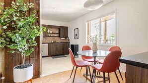 A modern kitchen with wooden cabinets, a dining area with red chairs, and a potted plant. - Downtown Mid-Century Modern Condo with Retro Vibes (Boise)